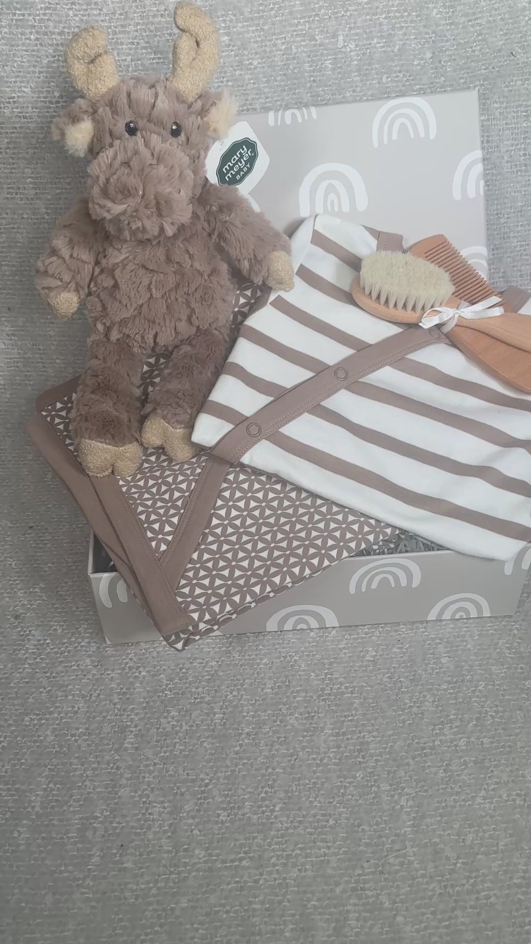 Video of a baby hamper with plush moose toy, blanket, and baby care items on a grey background