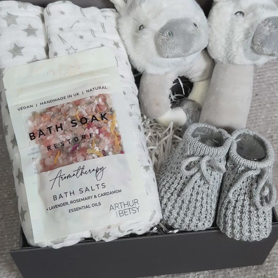 Video of a baby gift set with, bath salts, and plush zebra baby rattles and muslins in a box.