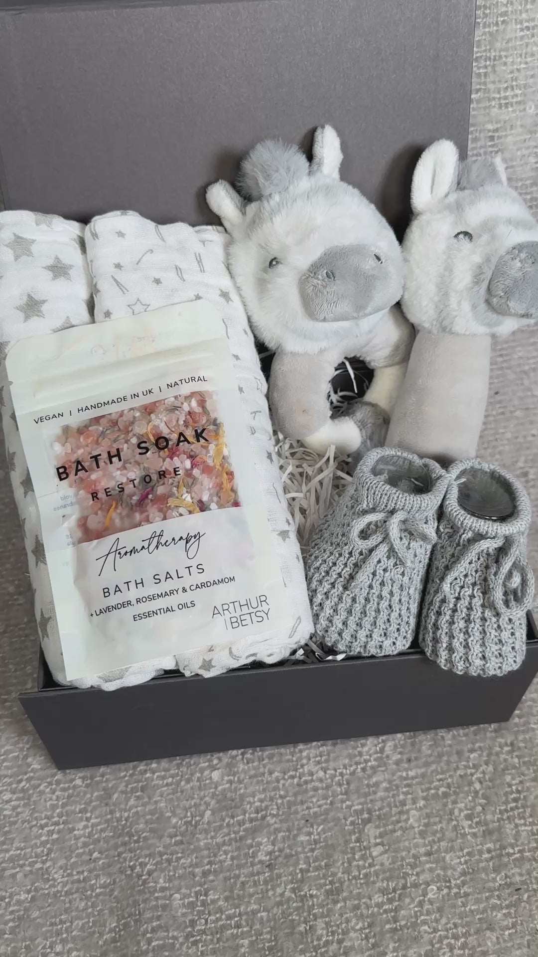 Video of a baby gift set with, bath salts, and plush zebra baby rattles and muslins in a box.