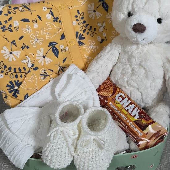 video of a baby girl hamper with  a bear and baby clothing
