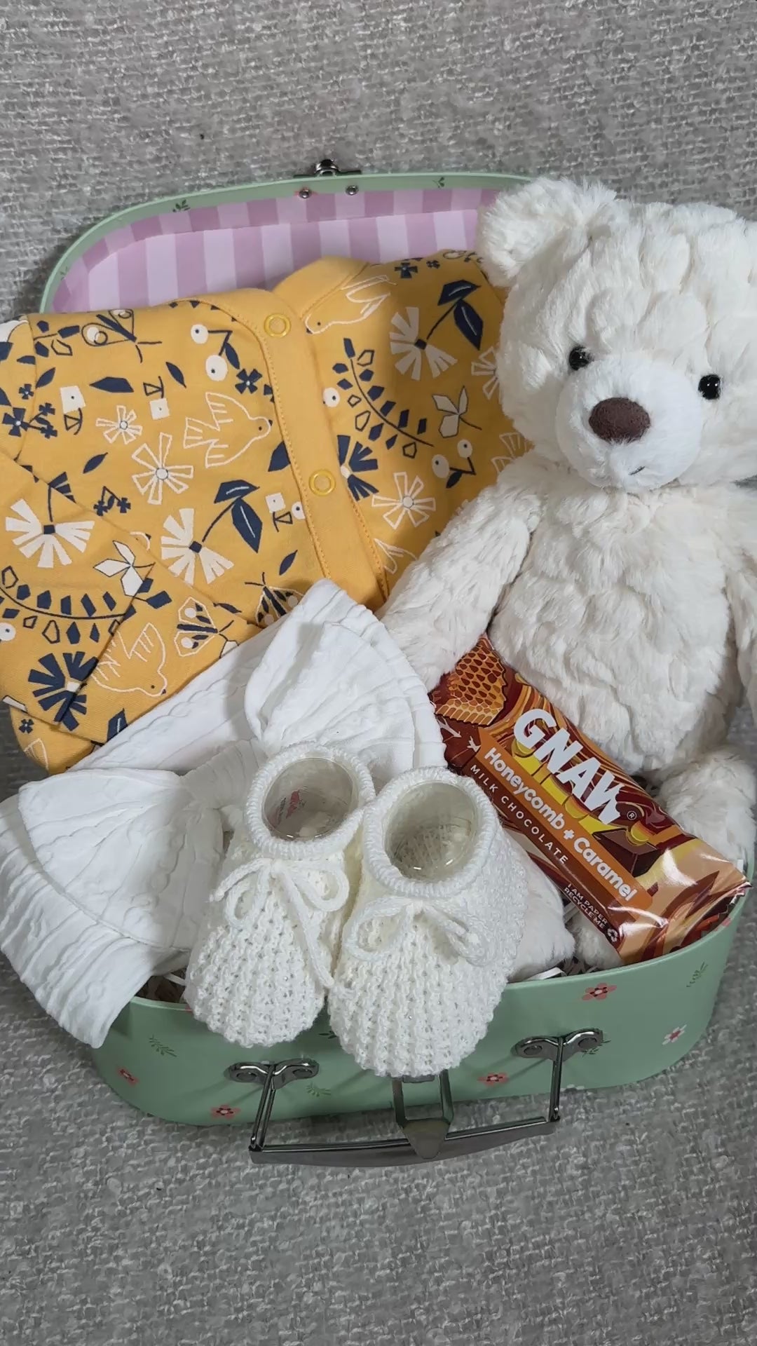 video of a baby girl hamper with  a bear and baby clothing