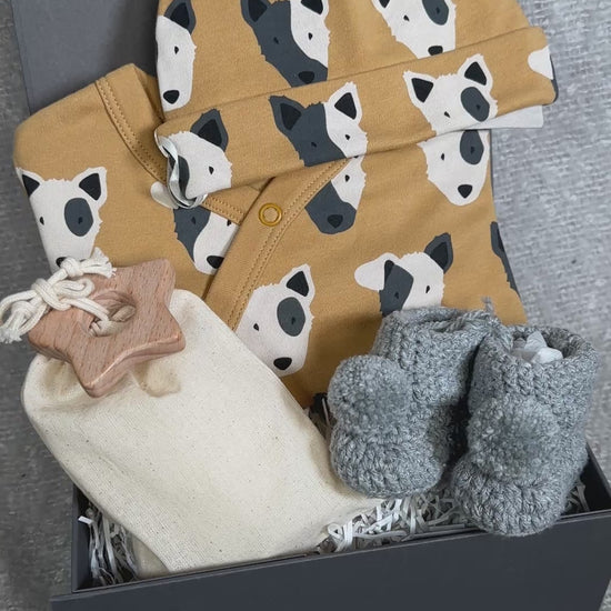 Video of a new baby hamper with dog print baby sleepsuit and matching baby knot hat and chrocheted baby booties.