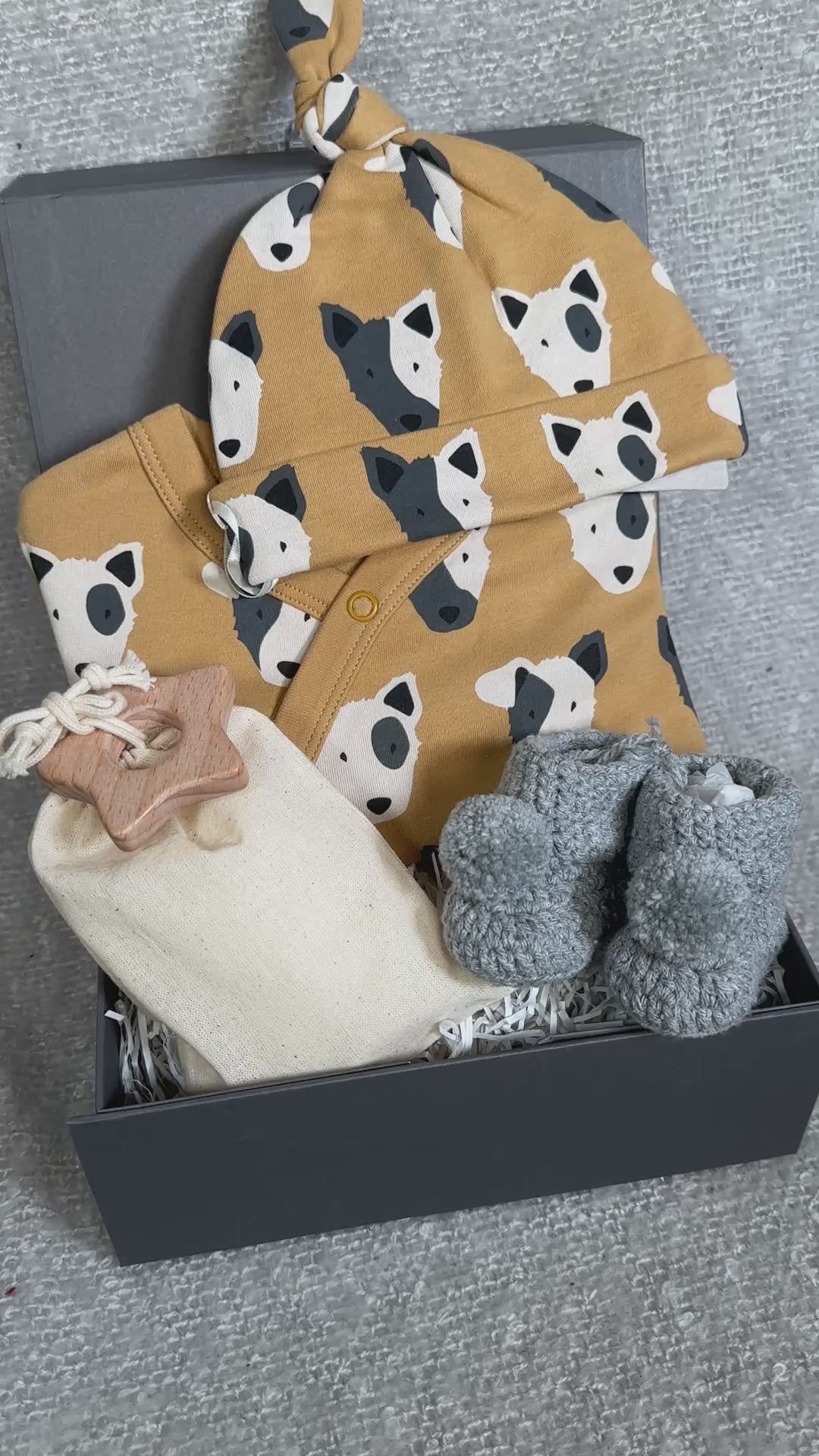 Video of a new baby hamper with dog print baby sleepsuit and matching baby knot hat and chrocheted baby booties.