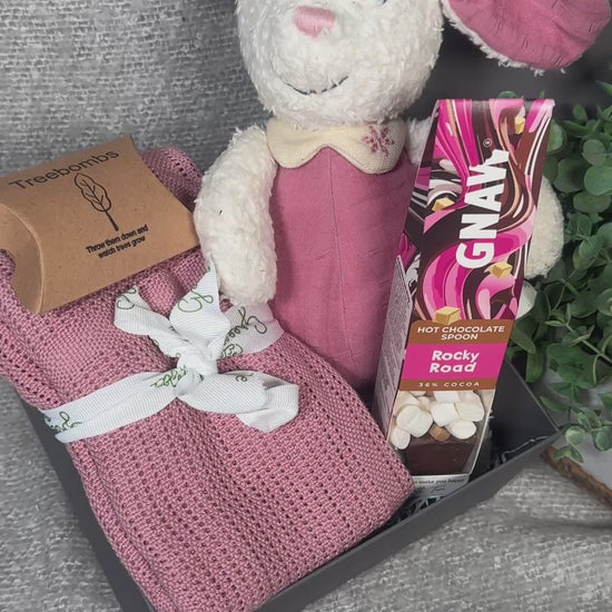 Video of pink baby girl hamper with bunny soft toy, baby blanket and hot chocolate stirrer.