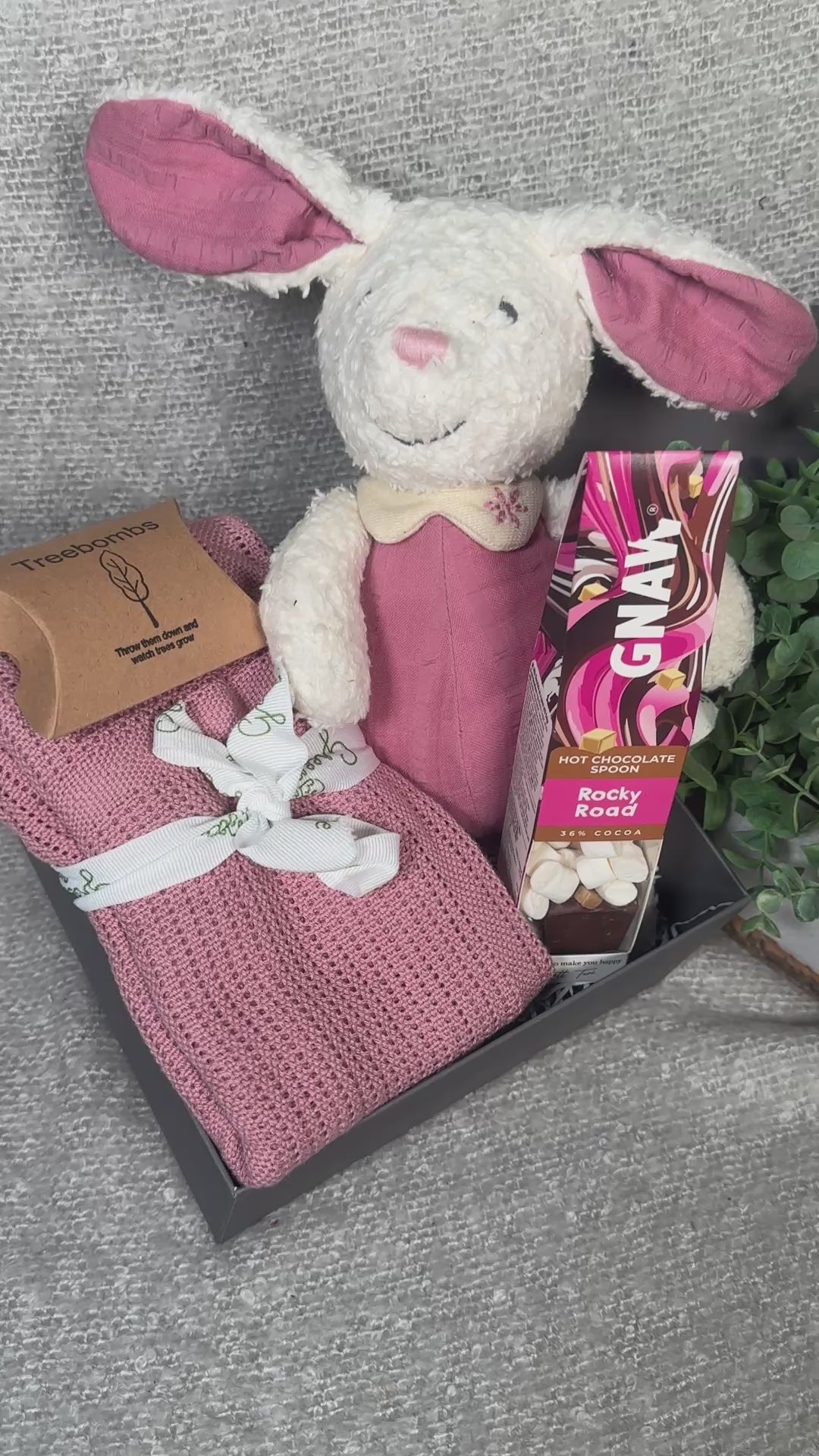 Video of pink baby girl hamper with bunny soft toy, baby blanket and hot chocolate stirrer.