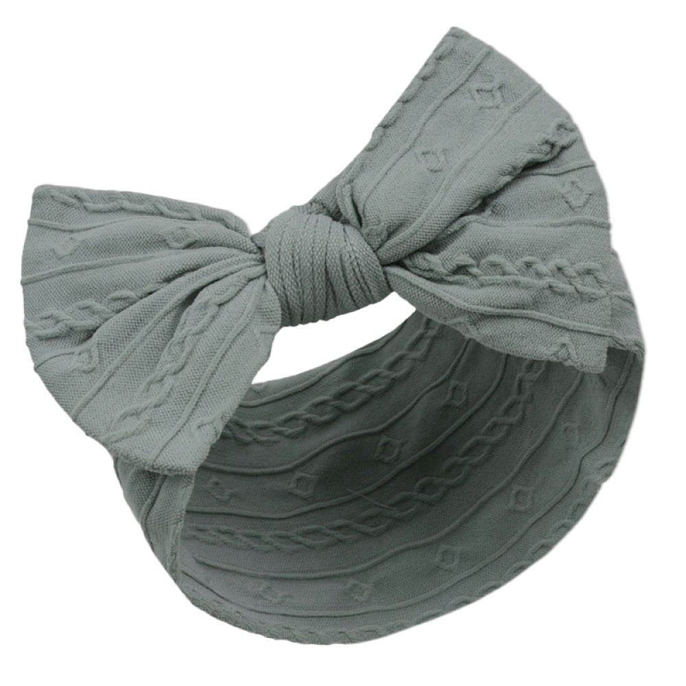 Green headband with a large knotted bow on a white background
