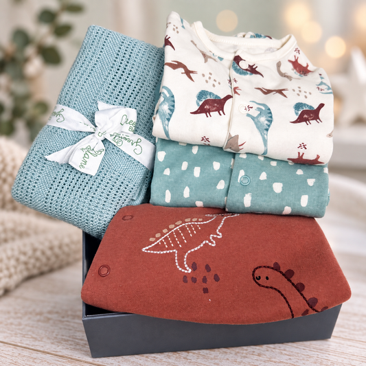 Dinosaur new baby boy hamper with dinosaur themed baby sleep suit and a sage green bamboo and cotton baby blanket in a baby keepsake box.