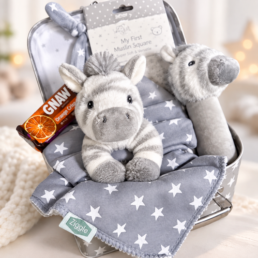 Unisex baby hamper grey and white with Zebra  plush toys, baby hat, and a chocolate bar on a grey background