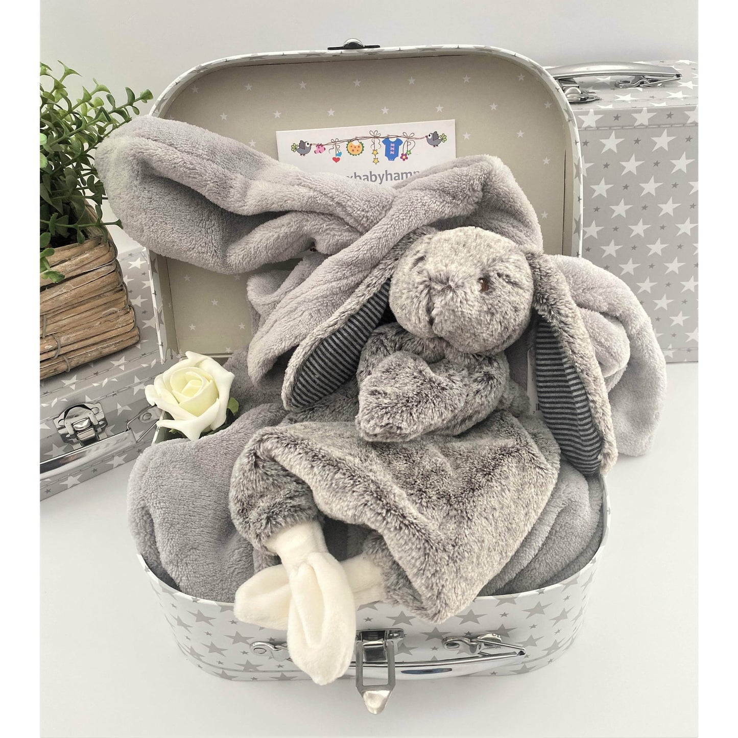 A baby keepsake case contains a grey baby dressing gown with long bunny ears on the hood and a Mary Meyer soft bunny lovey baby toy in grey and white.