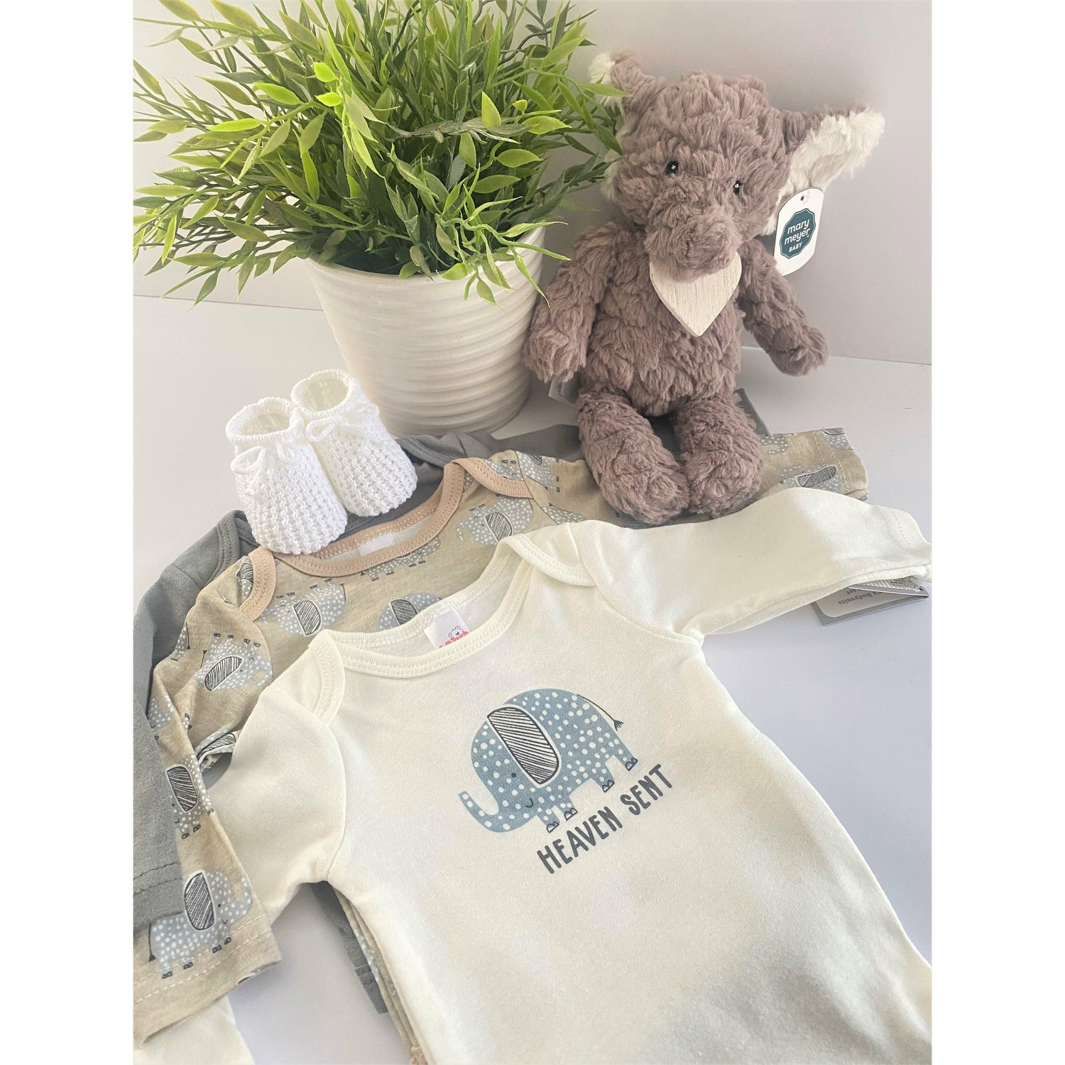 A set of 3 neutral baby bodysuit with an elephant theme one of which has the text " Heaven sent".