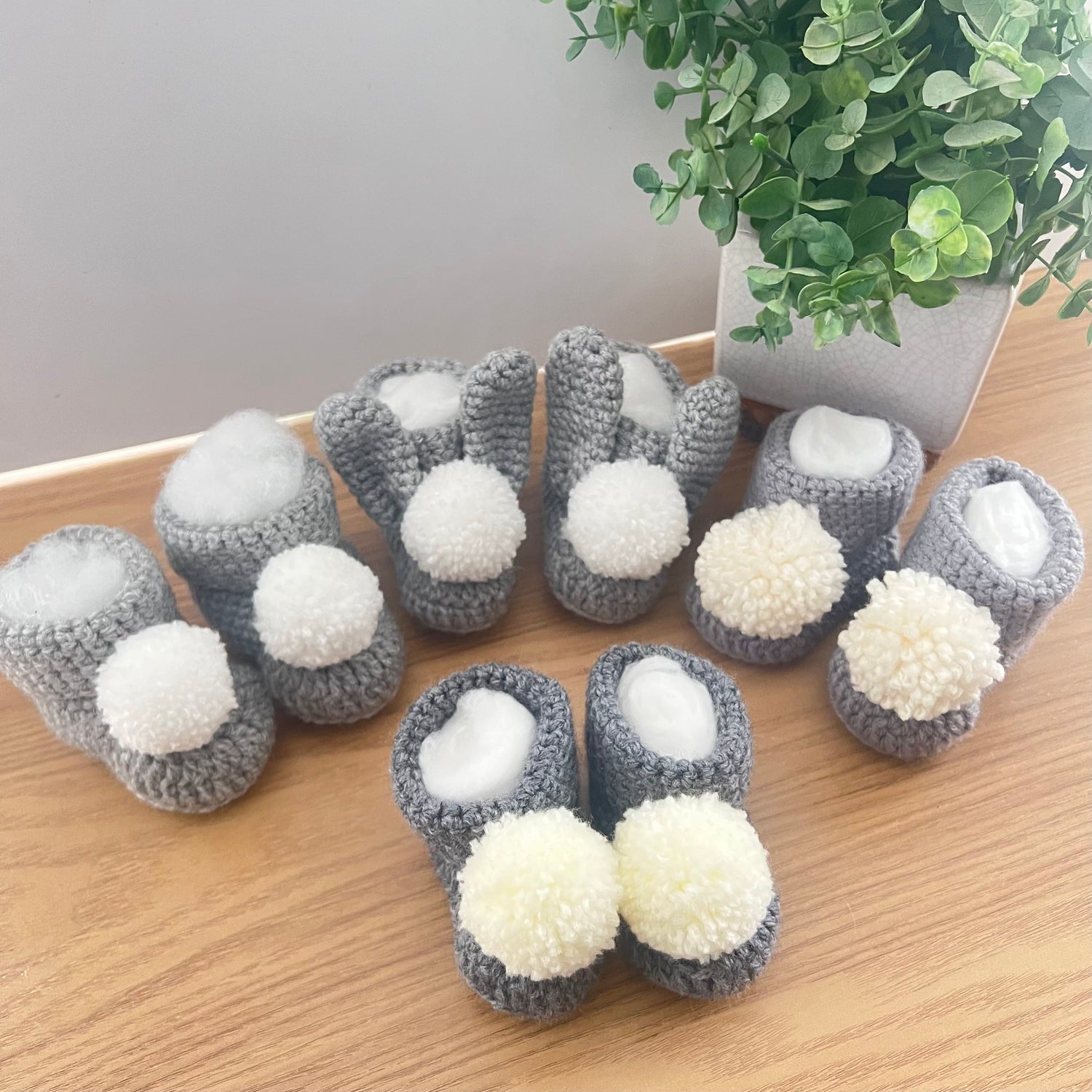 Crocheted baby bootees in grey and white with pom poms
