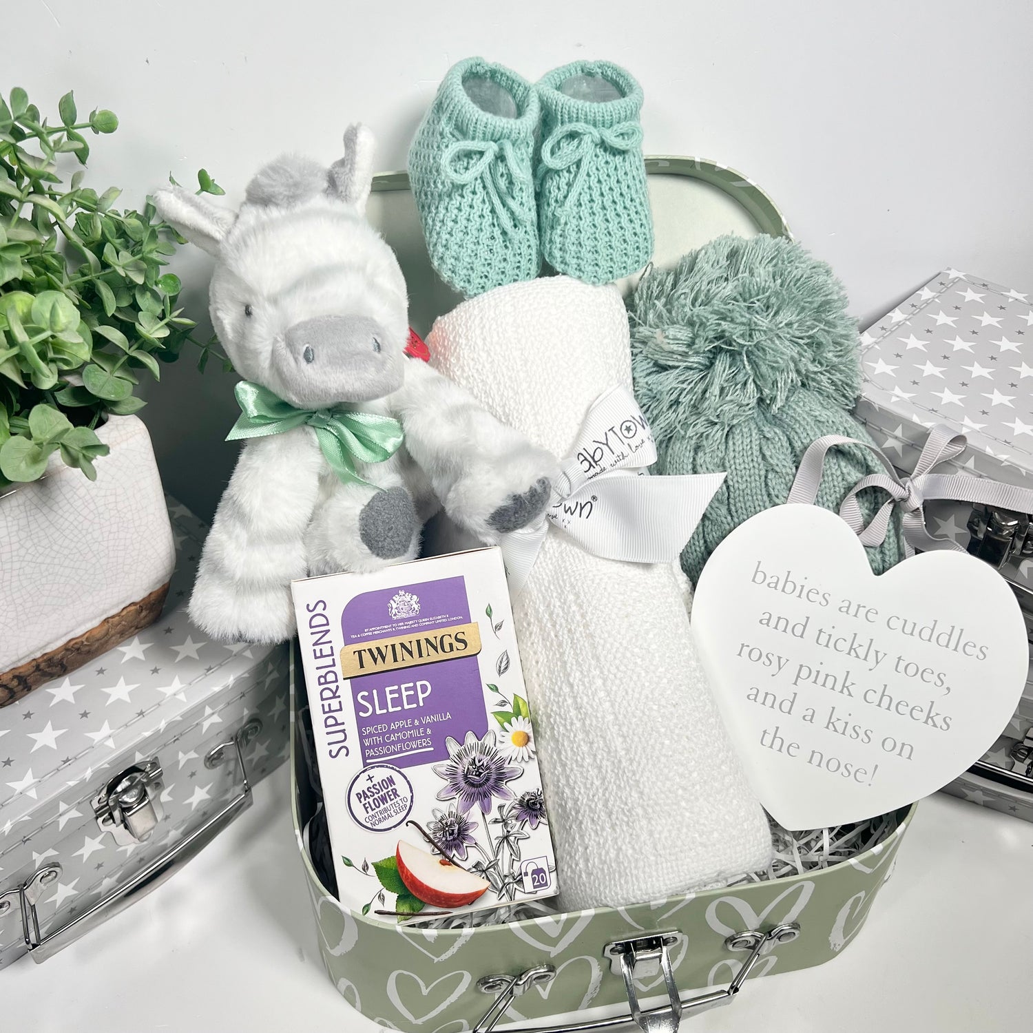 Unisex new baby gift containing a white cellular baby blanket, a green abby pompom hat, a Keeleco zebra soft toy, a nursery plaque and some \twining Sleep" teabags for the new parent/s.