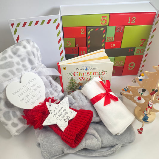 new mum advent calender gift includes a large advent calender with 24 individualboxes each filled with either a new baby  essenial or a gift for the new mum and dad. There is also a peter rabbit christmas wish book, a red baby pompom hat, a large white muslin square, a grey baby dressing gown, a grey and white soft baby blanket, a nursery plaque and and a ceramic Christmas tree decortaion that says "our first christmas as mummy and Daddy.